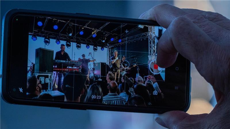 Ein Zuhörer hält das Konzert mit seinem Handy fest.