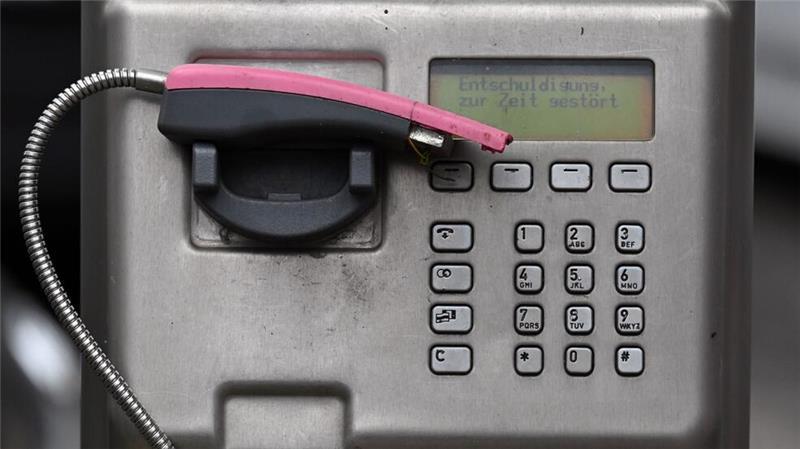 Ein abgebrochener Telefonhörer liegt in der Halterung eines deaktivierten Fernsprechers.