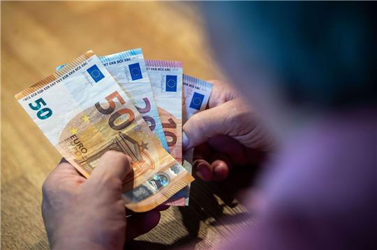 Ein älterer Mann sitzt an einem Tisch und zählt Geld.