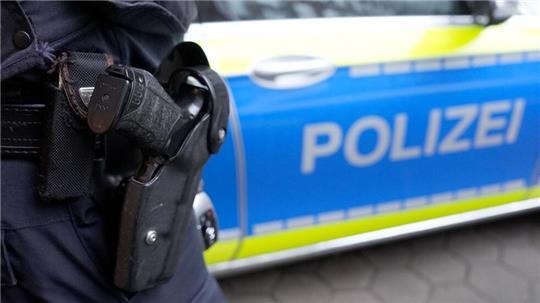 Ein Polizist steht vor einem Polizeiwagen.