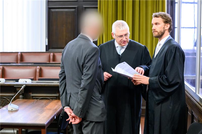 Neunjähriger stirbt bei Routine-OP – Urteil erneut verschoben Ein angeklagter Arzt (links) steht neben seinen Rechtsanwälten im Sitzungssaal des Landgerichts. Foto: Walzberg/dpa