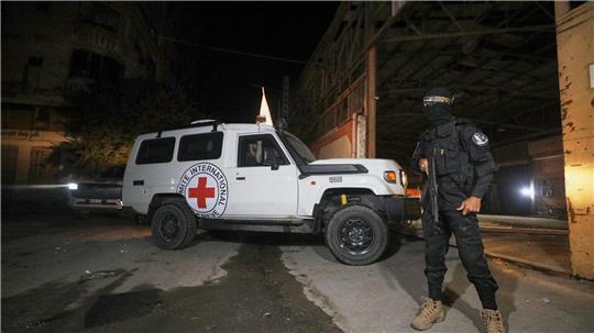 Ein bewaffneter Mann in der Uniform der al-Qassam-Brigaden, dem militärischen Flügel der Hamas, steht Wache, als Fahrzeuge des Roten Kreuzes in ein Lagerhaus einfahren.