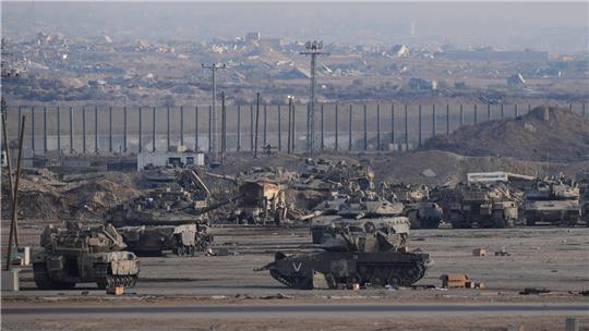 Ein bewaffneter Mann in der Uniform der al-Qassam-Brigaden, dem militärischen Flügel der Hamas, steht Wache, als Fahrzeuge des Roten Kreuzes ein Lagerhaus verlassen. In dem Lagerhaus sollen angeblich Särge mit den Leichen von vier verstorbenen Geiseln abgeholt und nach Israel gebracht werden.