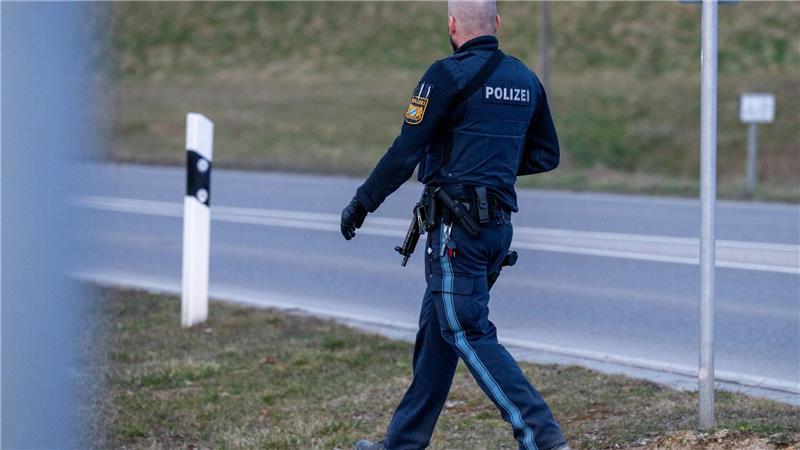 Zwei Tote bei zwei Feiern in Bayern - Täter weiter flüchtig Ein bewaffneter Polizist geht auf einer Straße am Ortsrand von Parsberg.