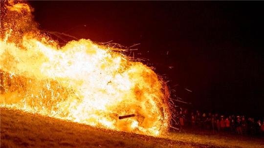 Ein brennendes Holzrad rollt den Osterberg hinunter in Richtung der Ortschaft Lügde beim jährlichen Osterräderlauf.