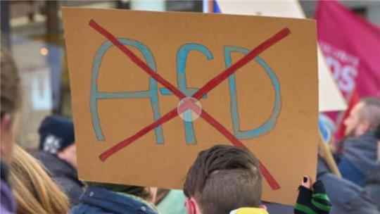 Ein durchgestrichenes AfD-Logo ist auf einem Schild bei einer Demo gegen Rechts zu sehen.