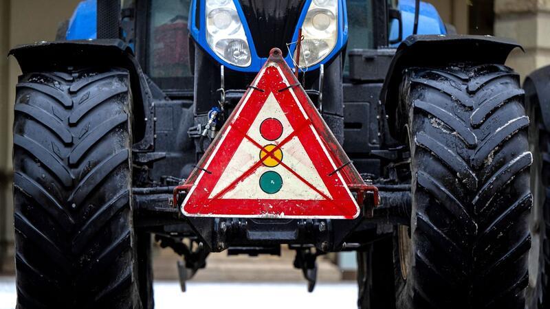Ein durchgestrichenes Verkehrsschild mit einer Ampel hängt während einer Demonstration von Landwirten an einem Traktor.