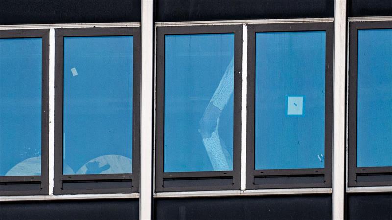 Ein eingeknickter Stützpfeiler ist durch ein Fenster zu sehen.