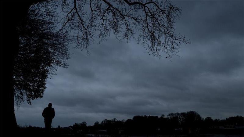 Ein einsamer Spaziergang unter grauem Himmel: Die frühen Dunkelstunden des Winters können die Stimmung drücken. Ursache ist vor allem der Lichtmangel.