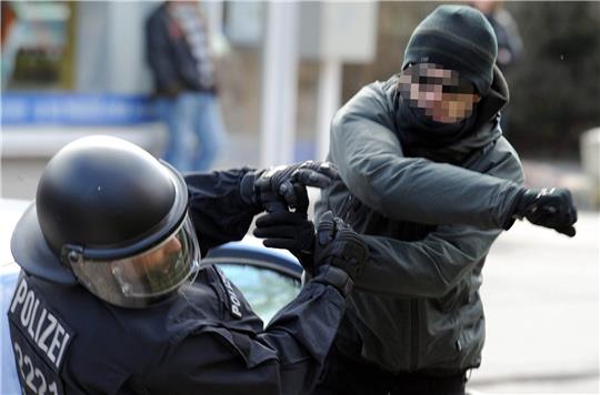 Ein gewalttätiger Demonstrant schlägt einen Polizeibeamten nieder (Symbolbild). Foto: Carsten Rehder/dpa
