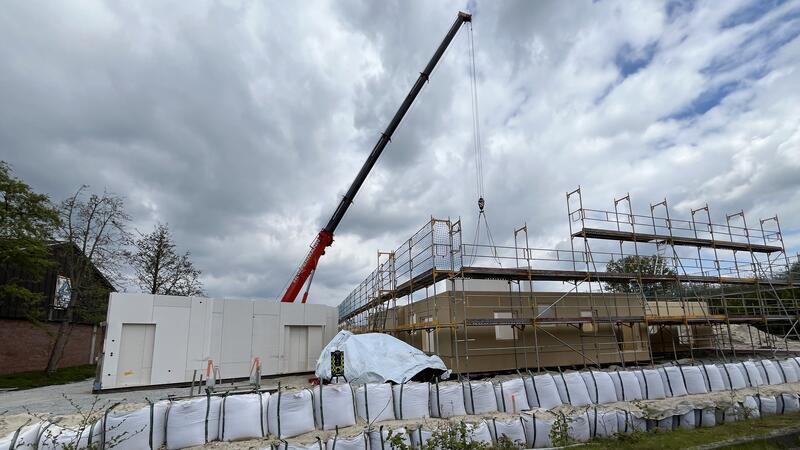 Ein großer Kran hebt ganze Hausteile und Innenwände auf die Bodenplatte der Kindertagesstätte in Buxtehude.