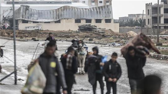 Ein israelischer Panzer ist zu sehen, während Palästinenser das Nasser-Krankenhaus und die angrenzenden Schulen verlassen.