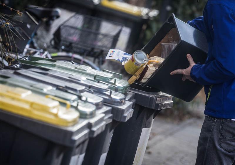 Ein junger Mann schüttet Abfall in eine Mülltonne. Foto: Frank Rumpenhorst/dpa