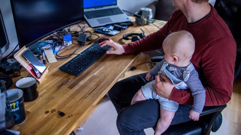 Ein junger Vater im Home-Office mit seinem sechs Monate alten Sohn.