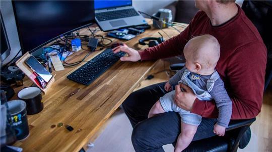 Ein junger Vater im Home-Office mit seinem sechs Monate alten Sohn.