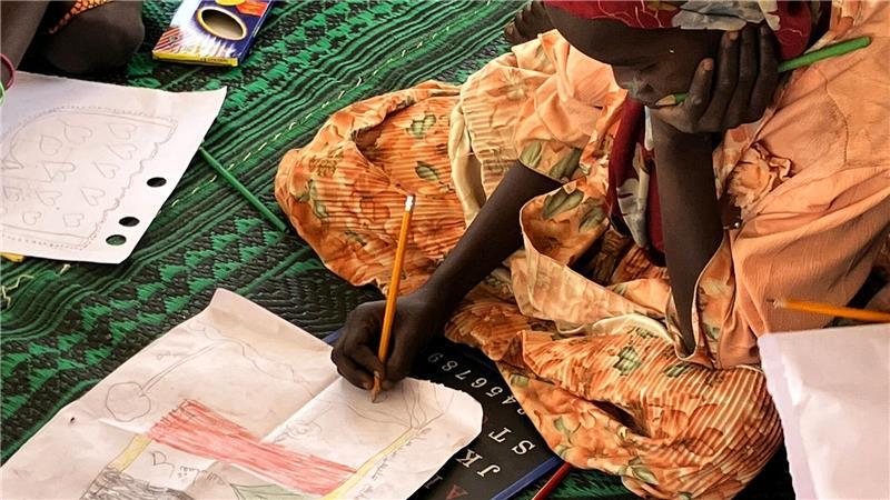 Ein kleines Mädchen malt die sudanesische Flagge.