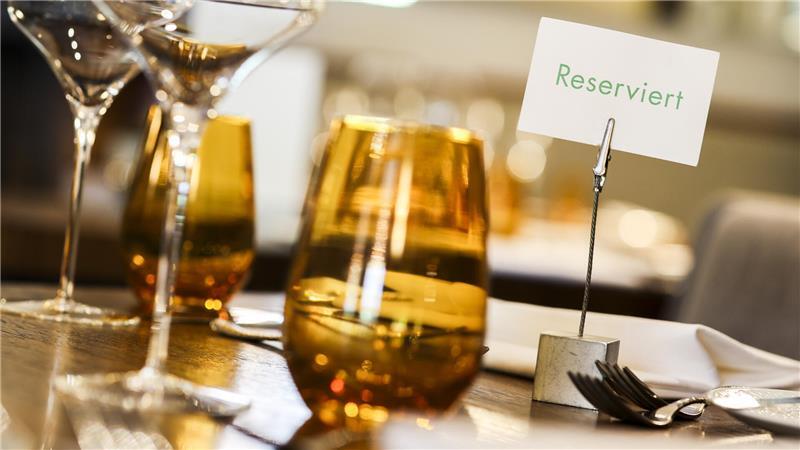 „Walk-in“-Trend? Wie die Gastronomie Gäste-Ghosting kontert Ein kleines Schild mit der Aufschrift „Reserviert“ und mehrere Gläser stehen auf einem eingedeckten Tisch in einem Restaurant.