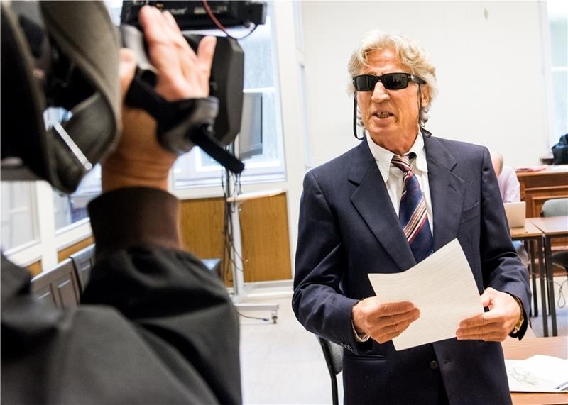 Ein mutmaßlicher Serienbankräuber redet im Landgericht vor Beginn der Verhandlung auf Journalisten ein. Foto: Bockwoldt/dpa