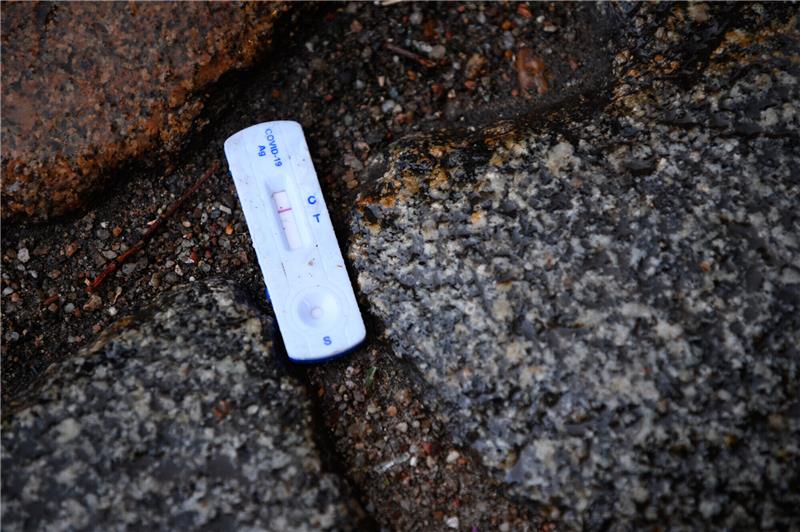 Ein negativer Corona-Test liegt zwischen Pflastersteinen auf dem nassen Boden. Foto: Jonas Walzberg/dpa