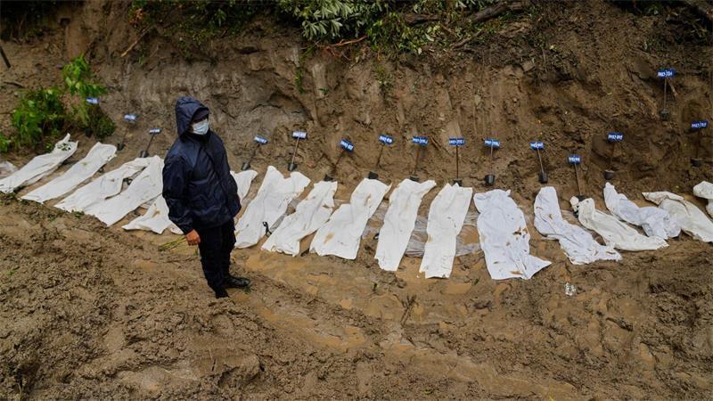 Nach Sturzflut: Zahl der Toten in Nepal steigt auf 1.127 Ein nepalesischer Polizist steht neben einer Reihe von Leichen von Opfern der Sturzflut, die zur Beisetzung in einem Massengrab aufgebahrt wurden.