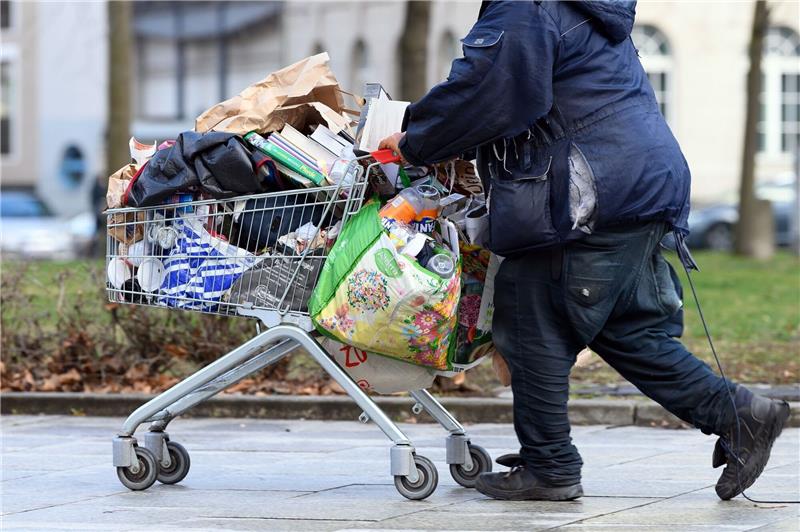 Armutskonferenz fordert Aktionsplan gegen Wohnungslosigkeit Ein obdachloser Mann schiebt einen Einkaufswagen über eine Fußgängerstraße in Berlin.