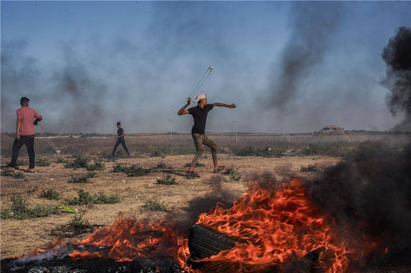 Ein palästinensischer Jugendlicher schleudert in Richtung israelischer Truppen.
