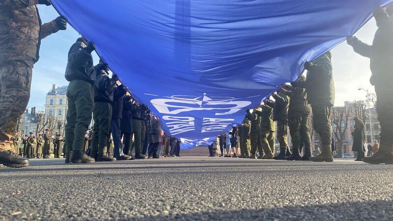 Ein riesige blaue Fahne mit der Aufschrift „Latvija Nato 20“ wird vor dem Freiheitsdenkmal entrollt. Lettland feiert 20 Jahre Nato-Mitgliedschaft.