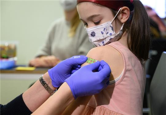 Ein siebenjähriges Mädchen bekommt bei einer Impfung gegen das Coronavirus ein Pflaster auf den Arm geklebt. Foto: Robert Michael/dpa-Zentralbild/dpa