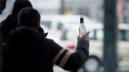 Ein stark alkoholisierter Mann gestikuliert am Hauptbahnhof in Hamburg mit einer Wodkaflasche in der Hand.