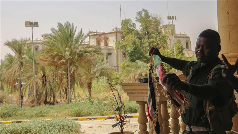 Sudans Regierungstruppen erobern Präsidentenpalast zurück Ein sudanesischer Soldat mit der Nationalfahne nach der Rückeroberung des Präsidentenpalasts in Khartum