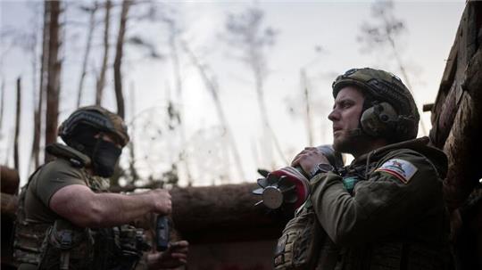 Ein ukrainischer Soldat trägt eine Mörsergranate, während er auf einen Feuerbefehl wartet.