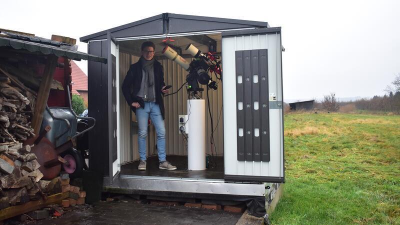 Johannes Lüth steht in seiner Sternwarte neben seinen Teleskopen.