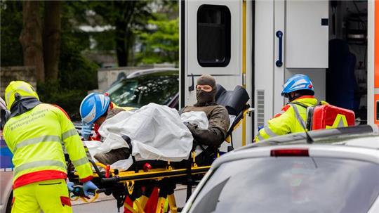 Ein verletzter Polizeibeamter wird vor einem Hochhaus in einen Krankenwagen gebracht.
