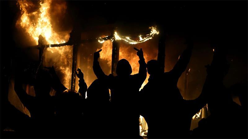 Ein vermummter Demonstrant streckt den Mittelfinger aus.