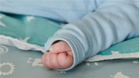 Ein wenige Wochen altes Baby ballt seine Hand zu einer kleinen Faust.