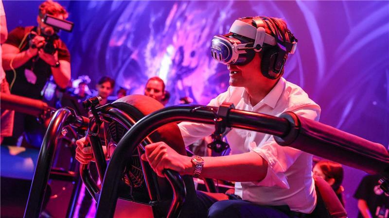 Ein wilder Ritt bei der Gamescom 2024: Hendrik Wüst auf einem „Drachen“, genauer gesagt mit virtueller Brille auf einem schwankenden Gestell.