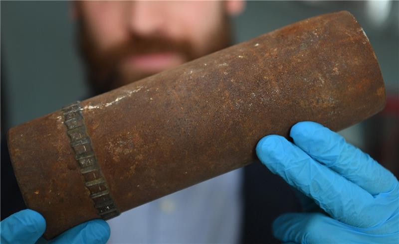 Ein wissenschaftlicher Mitarbeiter im Bereich Maritime Archäologie im Deutschen Schifffahrtsmuseum, hält eine Geschosshülse in seinen Händen. Foto: dpa