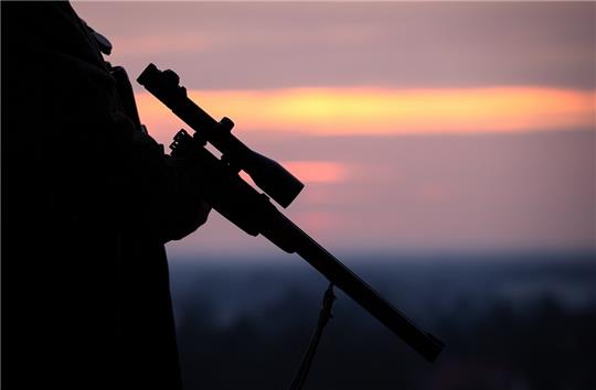 Ein Jäger hält sein Gewehr in der Abenddämmerung (Symbolbild). Foto: Friso Gentsch/dpa