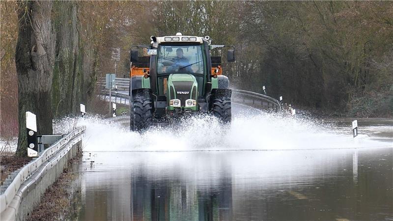 Ein Traktor fährt über die überschwemmte Lahnparkstraße in Heuchelheim.