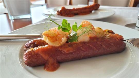Eine Bio-Rinder-Currywurst – hier in einer abgewandelten Surf & Turf-Variante mit Garnelen – wird künftig im Bistro „EIX“ im Badhotel Sternhagen in Cuxhaven auf der Karte stehen.