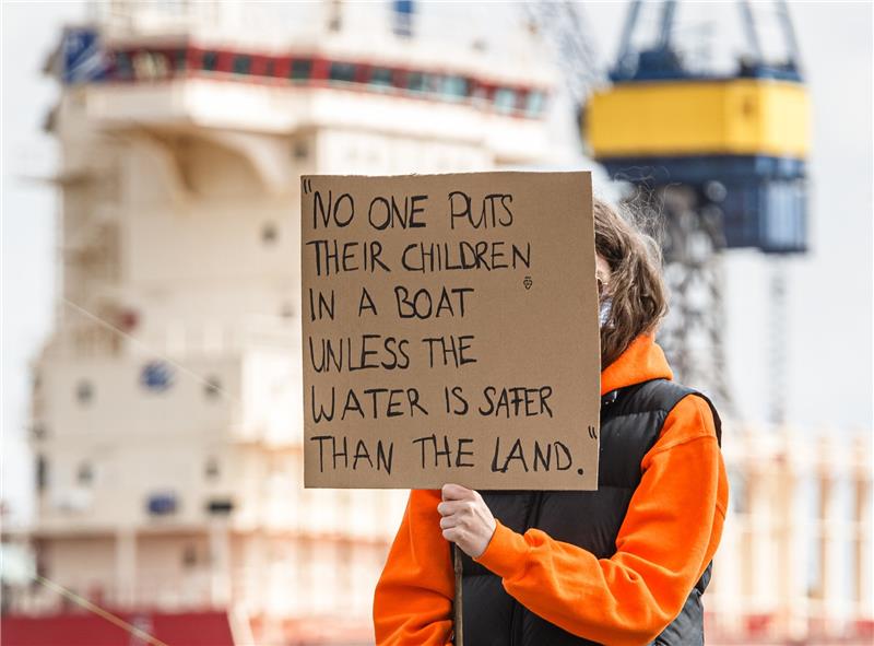 Flüchtlings-Demo kann stattfinden Eine Demonstrantin hält ein Schild mit der Aufschrift "No one puts their children in a boat, unless the water is saver than the land.". Archivfoto: Markus Scholz/dpa