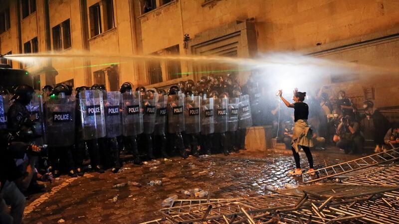 Mehr als 60 Festnahmen bei Protesten in Tiflis Eine Demonstrantin steht in Tiflis Bereitschaftspolizisten gegenüber.