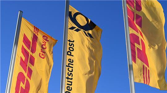 Eine Deutsche-Post-Fahne an der Konzernzentrale, umrahmt von DHL-Fahnen.
