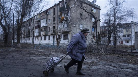Eine Einheimische geht zur Verteilungsstelle für humanitäre Hilfe vor einem Haus, das nach ukrainischen Angaben durch russischen Beschuss beschädigt wurde.