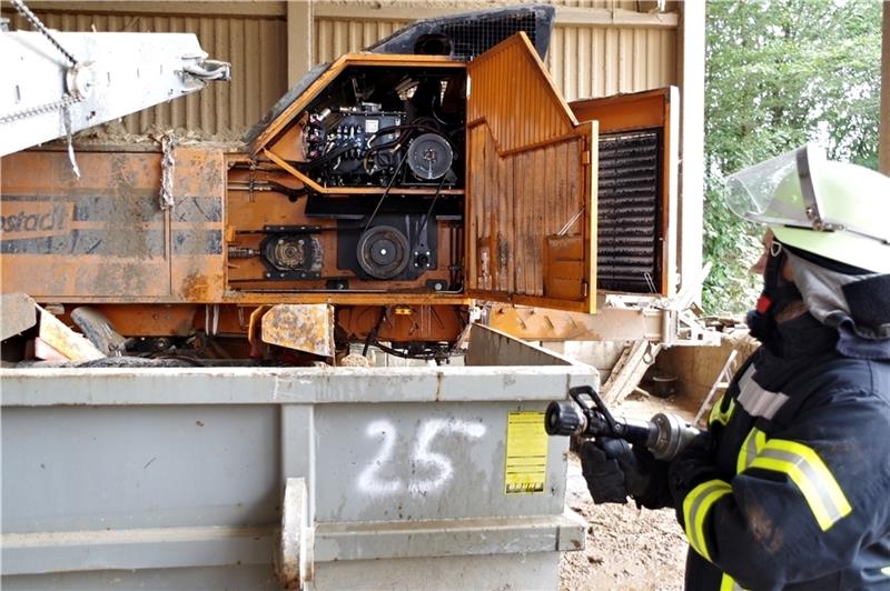 Eine Einsatzkraft der Feuerwehr steht mit Strahlrohr vor der Häckselmaschine auf dem Betriebsgelände des Recycling-Betriebes bereit. Foto Hillyer-Funke
