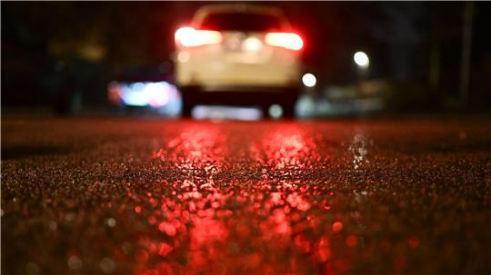 Eine Eisschicht liegt während gefrierenden Regens vor einem Auto.