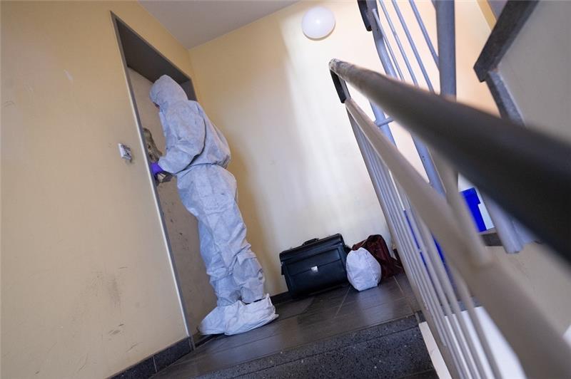 Eine Ermittlerin im Schutzanzug sichert Spuren an der Wohnungstür. Rettungskräfte von Feuerwehr und Polizei haben die Leiche eines 83-Jährigen in dessen Wohnung in Hamburg-Wilhelmsburg gefunden. Ersten Erkenntnissen zufolge ist der Mann gewaltsam getötet worden, wie die Polizei mitteilte. Foto: Jonas Walzberg/dpa