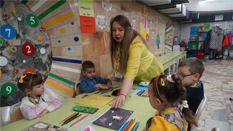 Eine Erzieherin verteilt in einem unterirdischen Kindergarten in Charkiw Malbücher und Stifte. Hier sind die Kinder vor russischen Raketenangriffen geschützt.