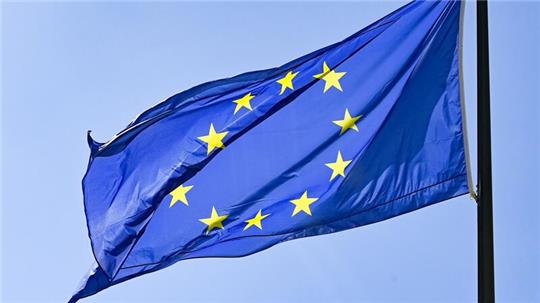 Eine Europaflagge weht vor blauem Himmel.