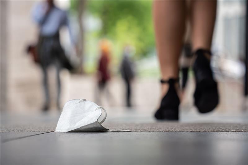 Eine FFP-2-Maske liegt in der Innenstadt auf dem Boden. Foto: Frank Rumpenhorst/dpa
